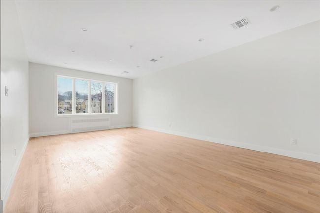 Empty room featuring light wood-type flooring and radiator heating unit | Image 18
