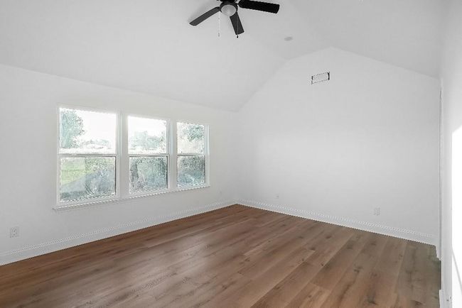 Additional living space with ceiling fan, visible vents, vaulted ceiling, wood finished floors, and baseboards | Image 13