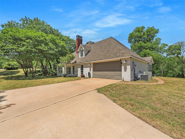 View of front of home featuring an attached garage, a chimney, brick siding, and a front yard | Image 29