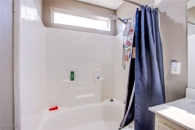 Full bathroom featuring shower / bath combo with shower curtain, vanity, and a textured wall | Image 19
