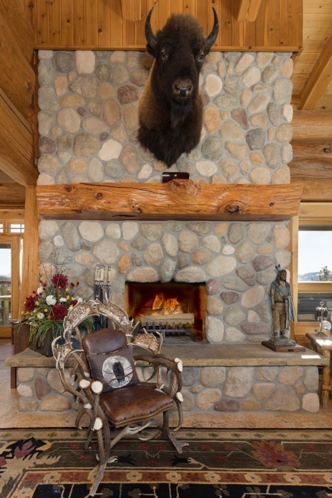 Main level great room with stone, wood burning fireplace, custom antler furniture, log mantel and cathedral ceiling. | Image 38