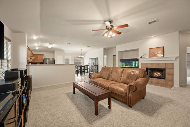 Inviting living room featuring plush carpet, a ceiling fan, and a spacious layout. Wall-mounted TV and entertainment console create the perfect spot to relax or entertain. | Image 10