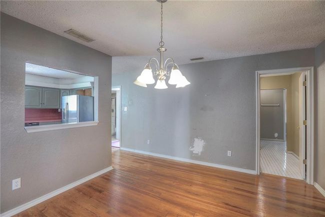 Unfurnished room featuring baseboards, visible vents, wood finished floors, and an inviting chandelier | Image 26