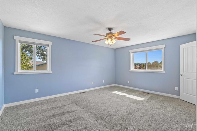Carpeted spare room featuring plenty of natural light, a textured ceiling, and ceiling fan | Image 17
