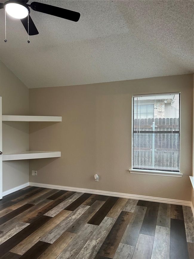 Spare room featuring a textured ceiling, ceiling fan, and dark wood-type flooring | Image 10