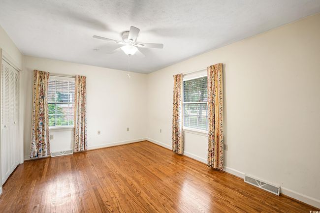 Empty room with healthy amount of natural light, wood finished floors, a ceiling fan, and baseboards | Image 23