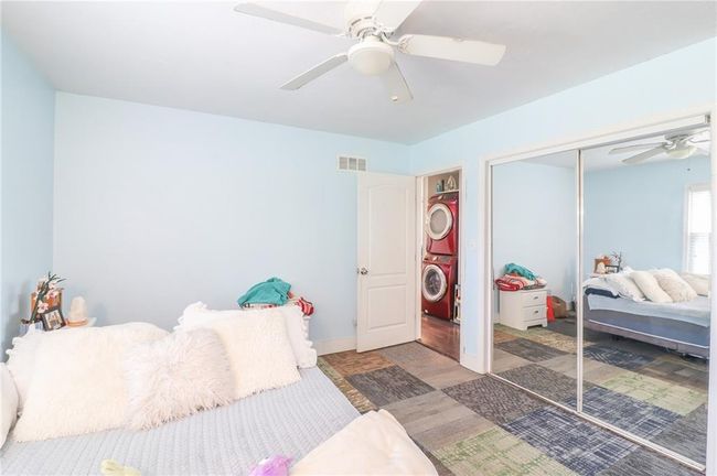 Bedroom featuring estacked washer and dryer, a closet, wood finished floors, and ceiling fan | Image 28