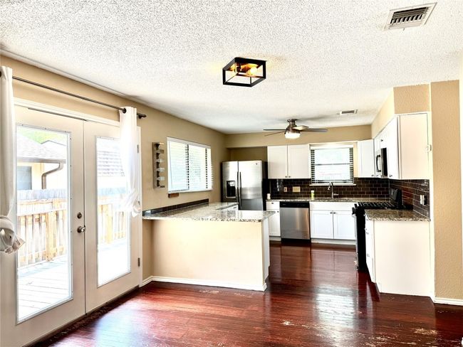 Kitchen with stainless steel appliances, french doors, a peninsula, dark wood-style floors, and a textured ceiling | Image 9
