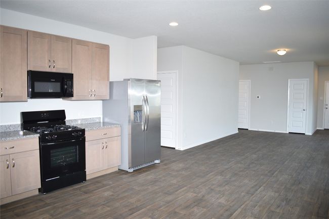 Kitchen featuring black appliances, recessed lighting, dark wood-style flooring, and light stone counters | Image 9