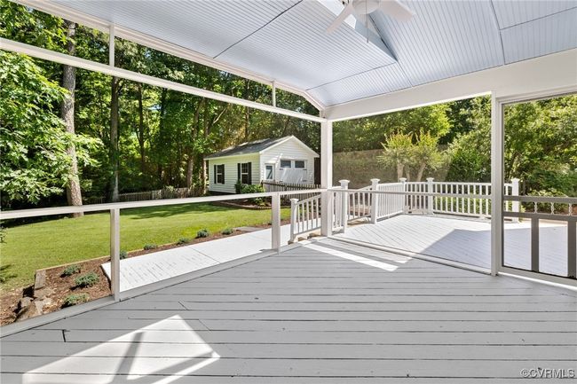 Screened-in porch with ceiling fan/light and door to rear deck/patio and private landscaped rear yard. | Image 35