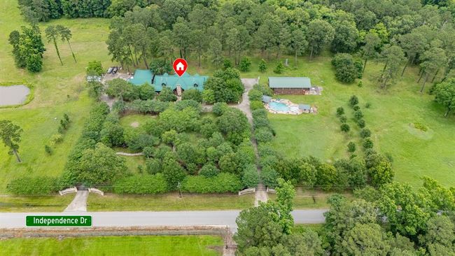 This aerial photo highlights a spacious property bordered by trees and open fields, marked by a red outline. It features a large home with a pond, nestled in a lush, private setting, conveniently located near Interstate 69. Ideal for those seeking tranquility with easy access to main roads. | Image 4