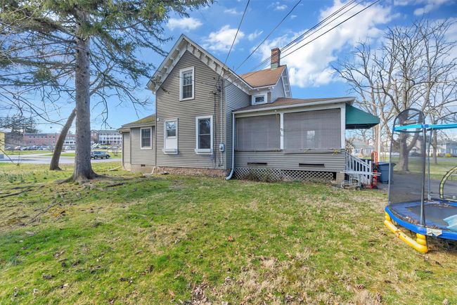 Rear view of house featuring a trampoline, a yard, a chimney, and crawl space | Image 47