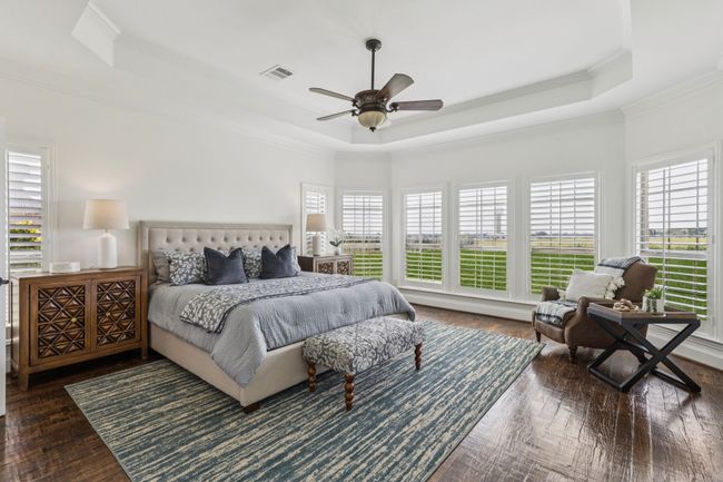 Primary bedroom featuring a tray ceiling, crown molding and a wall of windows to the backyard. | Image 18
