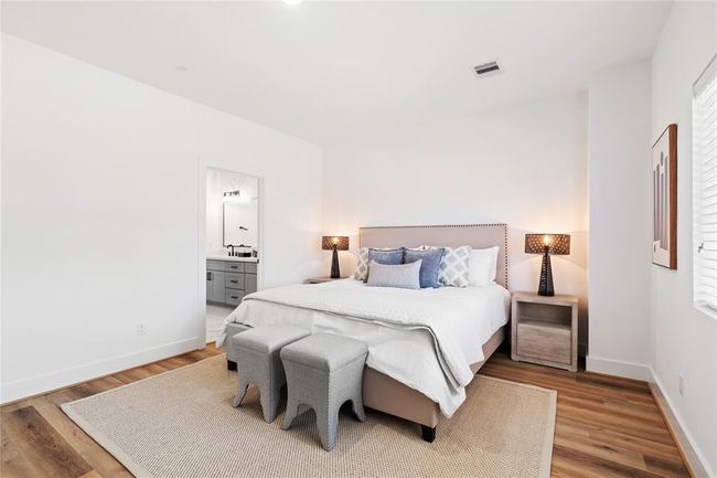 Step into your luxurious primary suite, where high ceilings, expansive windows, and premium flooring create a bright and inviting retreat. This thoughtfully designed space offers both comfort and style, perfect for unwinding at the end of the day. | Image 18