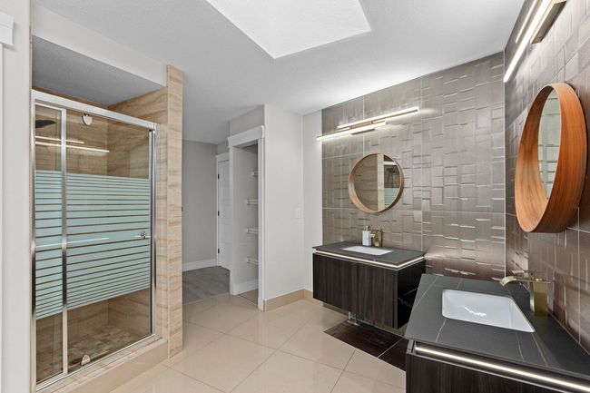 Bathroom with a sink, tile walls, tile patterned floors, and a shower stall | Image 26