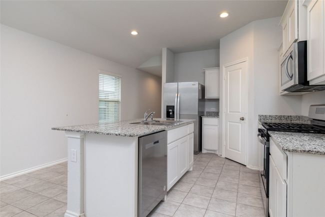 Kitchen featuring stainless steel appliances, a sink, light tile patterned floors, a center island with sink, and recessed lighting | Image 7