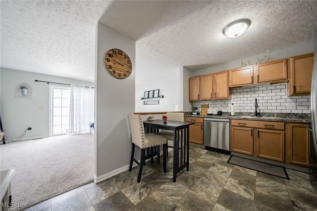 Kitchen with dishwasher, a textured ceiling, and dark carpet | Image 5