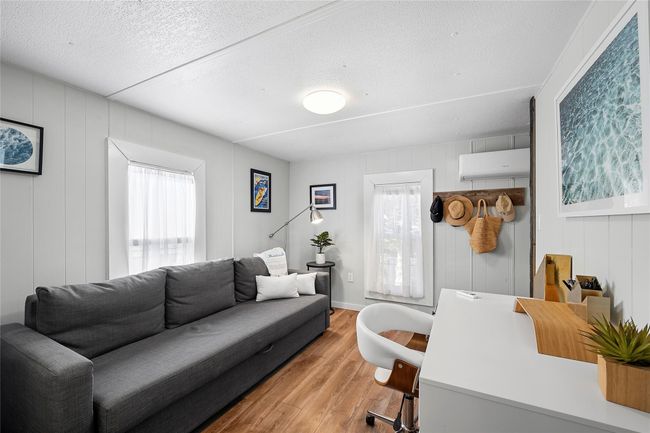 Bedroom featuring a textured ceiling, light wood-style floors, a healthy amount of sunlight, and a wall mounted AC | Image 11
