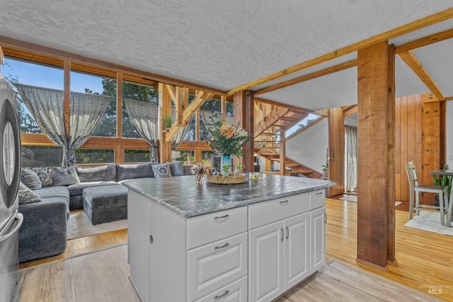 Kitchen featuring light wood-style floors, white cabinets, a textured ceiling, a kitchen island, and open floor plan | Image 8