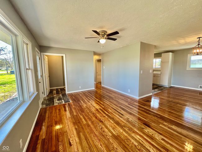unfurnished room with baseboards, hardwood / wood-style floors, and ceiling fan with notable chandelier | Image 6