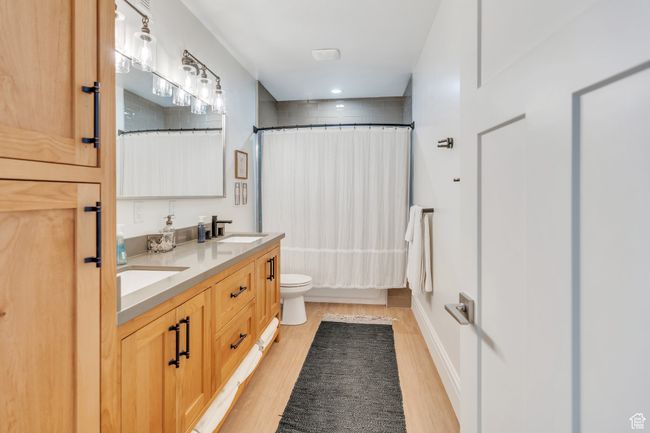 Bathroom featuring wood finished floors, double vanity, shower / bath combo with shower curtain, and recessed lighting | Image 54
