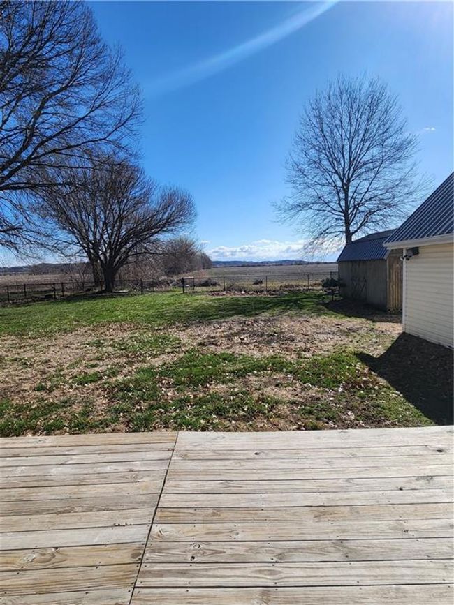 View of yard with a storage unit, fence, a rural view, an outdoor structure, and a wooden deck | Image 5