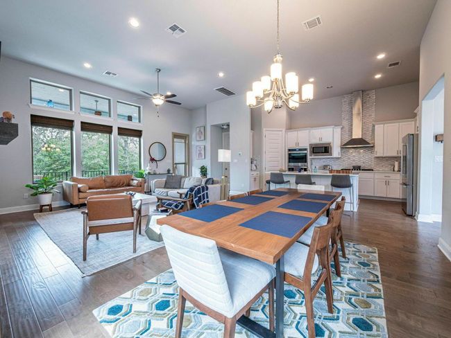 Dining space featuring a chandelier, ceiling fan, a high ceiling, dark wood finished floors, and recessed lighting | Image 9