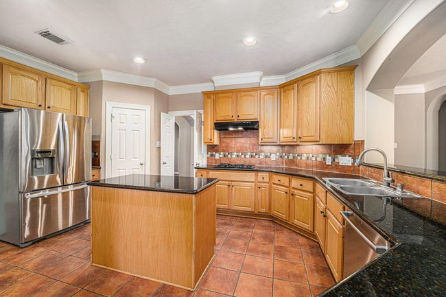Chef's dream kitchen boasts beautiful countertops, lots of cabinetry, a central island, and a walk-in pantry—perfect for everyday living and entertaining. | Image 13