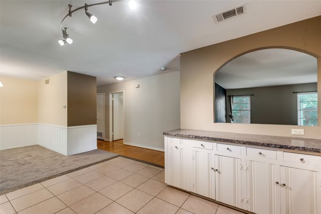 Kitchen featuring light tile patterned floors, a wainscoted wall, arched walkways, and visible vents | Image 10