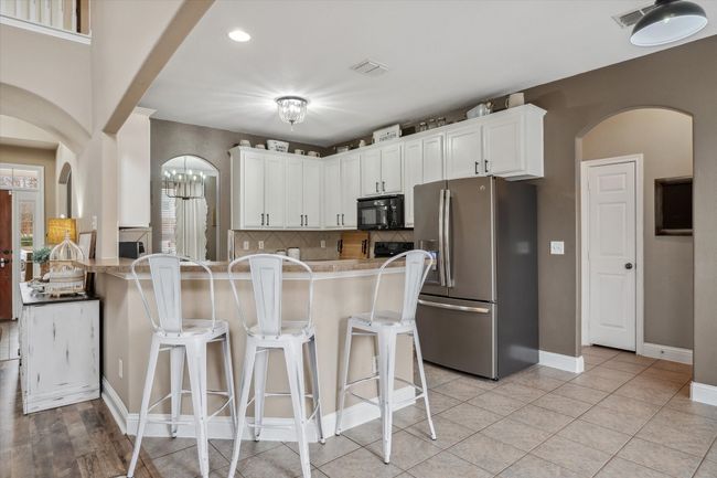 Kitchen featuring stainless steel fridge, visible vents, black microwave, and arched walkways | Image 8