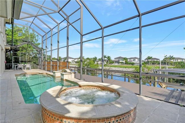 View of pool with a lanai, a water view, a pool with connected hot tub, and a patio area | Image 33