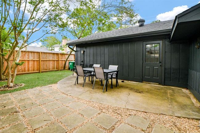 This backyard features a cozy patio area with a table and chairs, surrounded by a wooden fence and some greenery, perfect for outdoor dining and relaxation. | Image 42