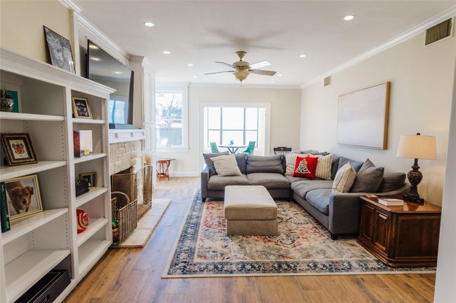 Living room with ceiling fan, light hardwood / wood-style flooring, ornamental molding, and a fireplace | Image 10