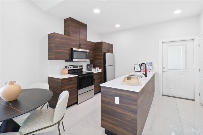 Kitchen with appliances with stainless steel finishes, sink, dark brown cabinets, and kitchen peninsula | Image 4