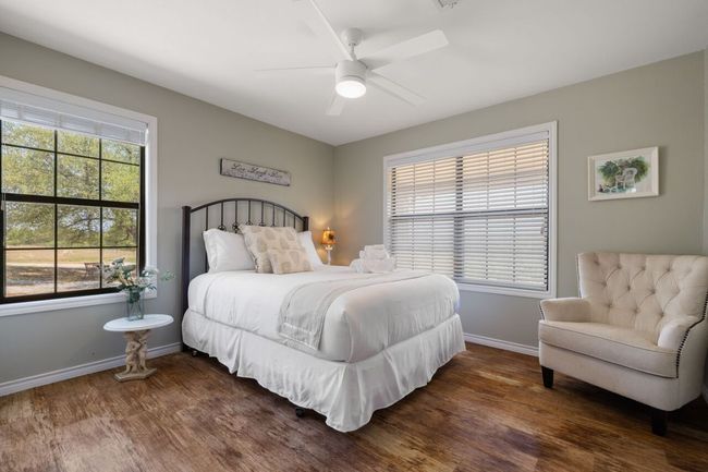 Bedroom with dark wood-type flooring, baseboards, and a ceiling fan | Image 29