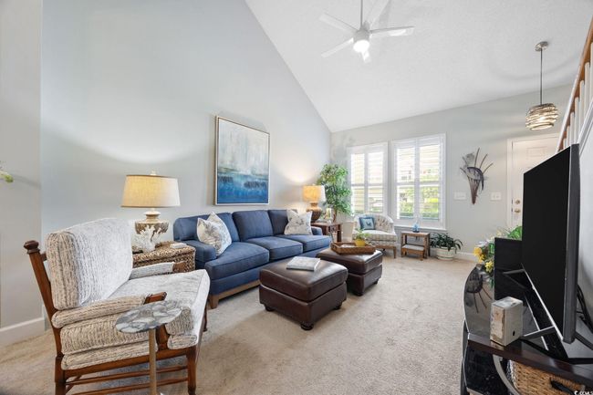 Living room featuring light colored carpet, high vaulted ceiling, and a ceiling fan | Image 7