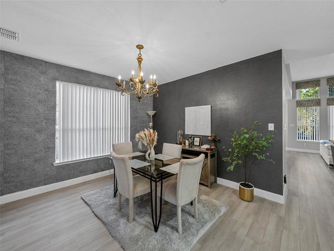 Dining room with visible vents, light wood-style flooring, baseboards, and a chandelier | Image 12