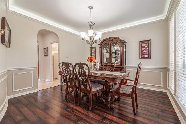 A gorgeous formal dining room features hardwood flooring, crown & box molding, custom paint, and fabulous uplighting that surely makes a statement in this room! | Image 16