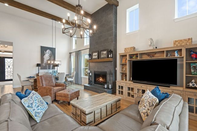 Living area featuring a chandelier, beamed ceiling, a fireplace, and wood finished floors | Image 18