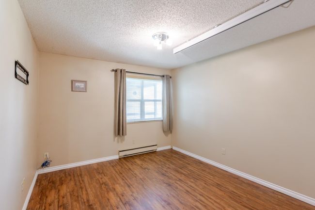 Bedroom with wood finished floors, a textured ceiling, ceiling lift tracks, baseboards, and baseboard heating | Image 23