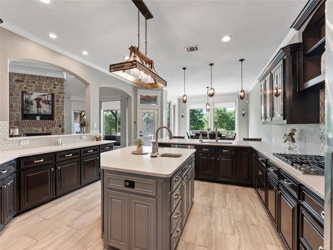 Kitchen featuring arched walkways, light countertops, a peninsula, stainless steel gas stovetop, and backsplash | Image 17