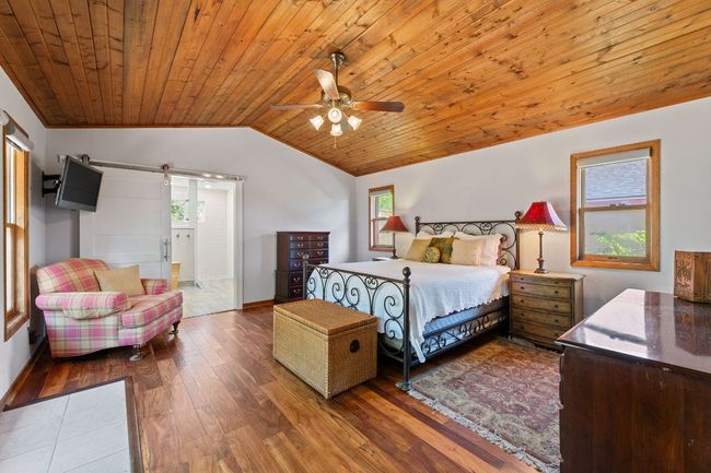 The primary bedroom has a wood ceiling, patio access and an attached full bathroom. | Image 11