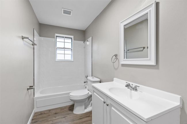 Full bath with toilet, vanity, shower / bathing tub combination, wood finished floors, and visible vents | Image 15