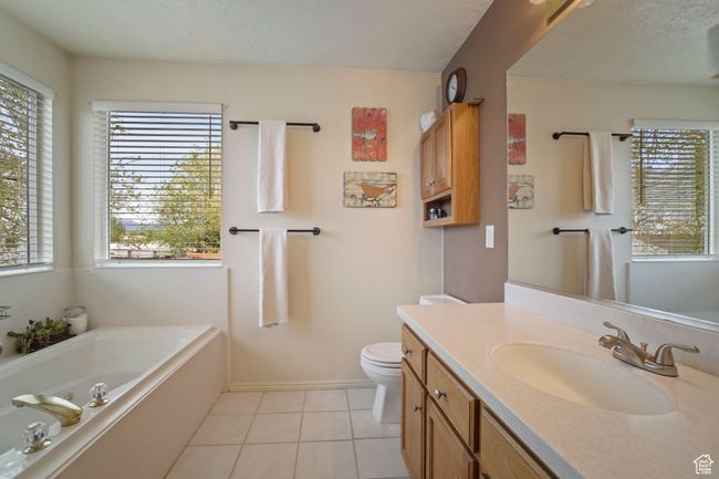 Bathroom with vanity, a bath, tile patterned floors, toilet, and baseboards | Image 12