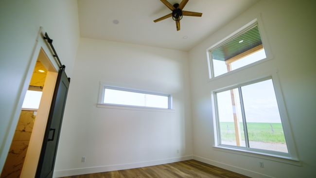 Spare room featuring a ceiling fan, a barn door, and wood finished floors | Image 32
