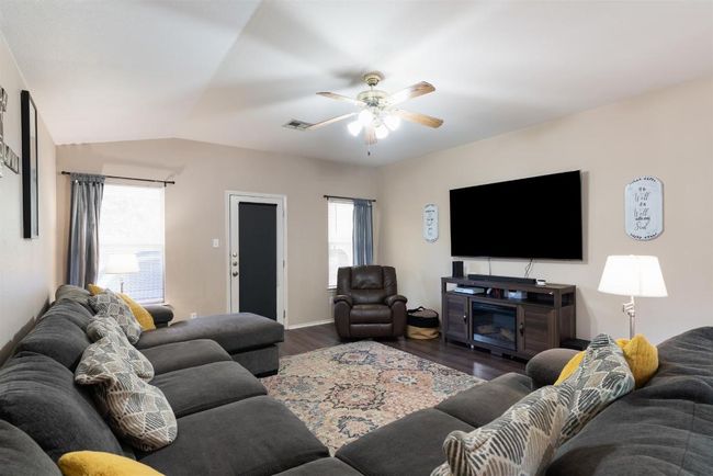 Living area with wood finished floors, plenty of natural light, lofted ceiling, and ceiling fan | Image 8