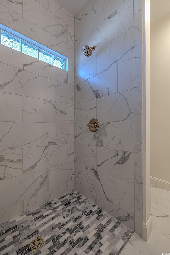 Full bath featuring marble look tiles and tiled shower | Image 15