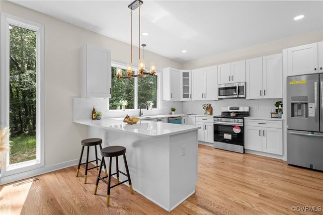 Kitchen with appliances with stainless steel finishes, healthy amount of natural light, a peninsula, white cabinetry, and recessed lighting | Image 4