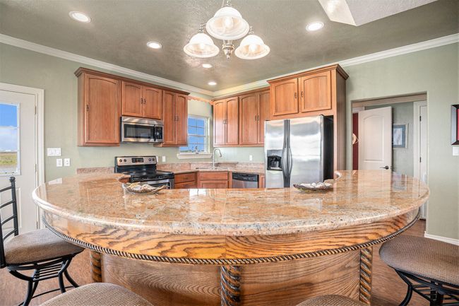 This kitchen boasts beautiful granite countertops, ample cabinet space for storage, and stainless steel appliances. The custom woodwork adds a touch of elegance and sophistication to the space. | Image 9