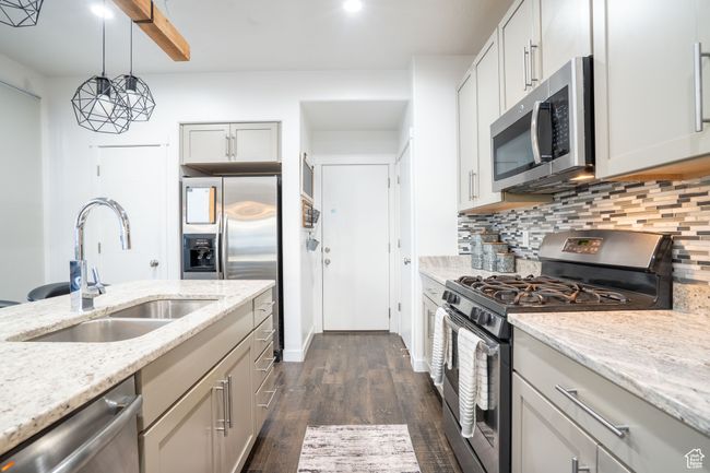 Kitchen with appliances with stainless steel finishes, tasteful backsplash, dark wood finished floors, and light granite counters with gas range. | Image 4